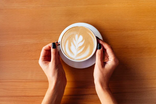 Žena ruce s šálkem horké chutné kávy v kavárně — Stock fotografie