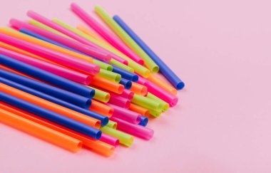 meyve suyu için renkli borular ve pembe arka planda kokteyller.