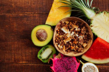 Kahverengi ahşap arka plan üzerinde Tropik taze yaz meyveleri ve granola tohumları