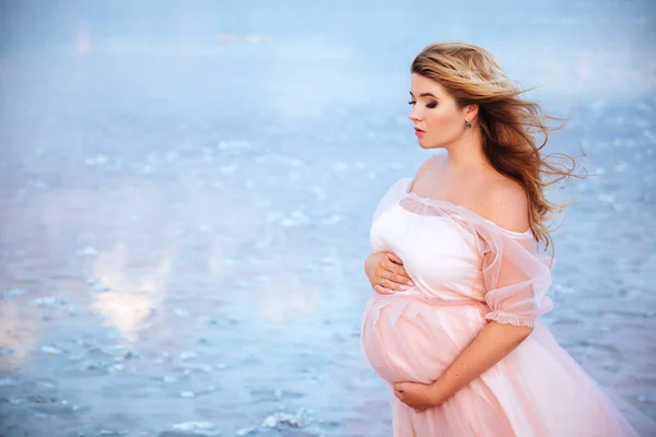 Bella giovane donna incinta godendo il sole sul lago rosa — Foto Stock