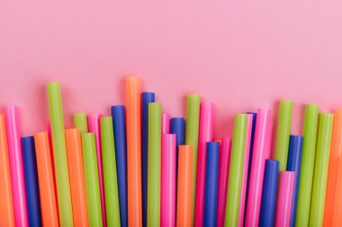 meyve suyu için renkli borular ve pembe arka planda kokteyller.