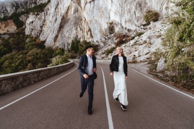 Yeni evli genç çift, gelin ve damat öpüşüyor, mükemmel dağ manzarasında kucaklaşıyorlar.