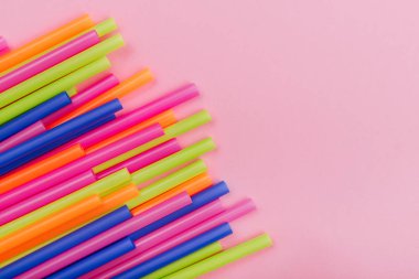 meyve suyu için renkli borular ve pembe arka planda kokteyller.