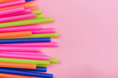 meyve suyu için renkli borular ve pembe arka planda kokteyller.