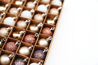 Altın Noel süslemeleri beyaz arka planda kutuda.