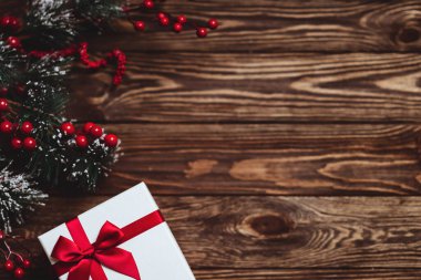 Koyu ahşap arka planda kırmızı kurdeleli Noel hediyesi