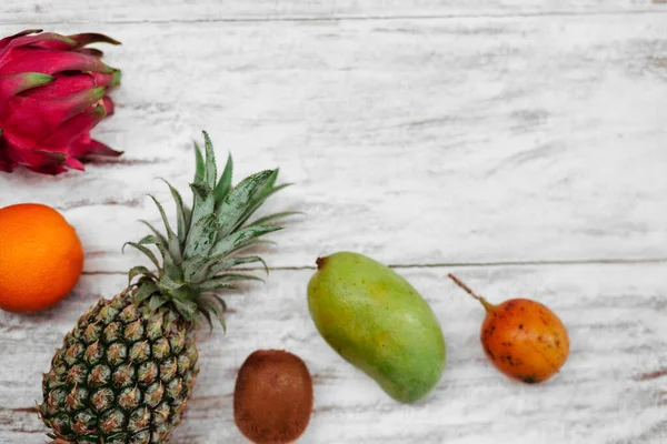 Tropische Früchte liegen auf einer hölzernen weißen Oberfläche. — Stockfoto