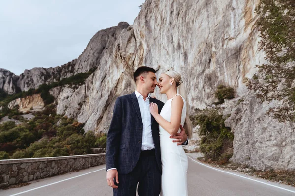 Joven pareja recién casada, novia y novio besándose, abrazándose a la vista perfecta de las montañas — Foto de Stock