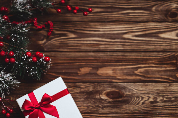 Рождественский подарок с красной лентой на темном деревянном фоне
