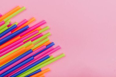 meyve suyu için renkli borular ve pembe arka planda kokteyller.