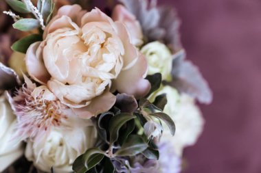 Zengin bir demet pembe şakayık ve leylak çiçekleri, cam vazoda yeşil yaprak.