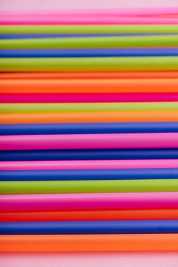 meyve suyu için renkli borular ve pembe arka planda kokteyller.