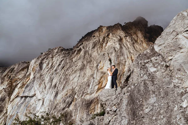 Młoda para nowożeńców, narzeczona i pan młody całujący się, przytulający się na doskonały widok na góry — Zdjęcie stockowe