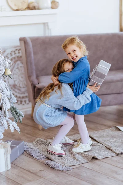 Dwa słodkie urocze siostrzyczki w pobliżu choinki w przytulnym salonie. — Zdjęcie stockowe