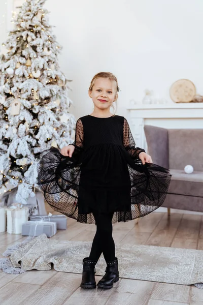 Маленька дівчинка з різдвяними подарунками біля ялинки — стокове фото