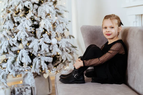 Маленька дівчинка з різдвяними подарунками біля ялинки — стокове фото