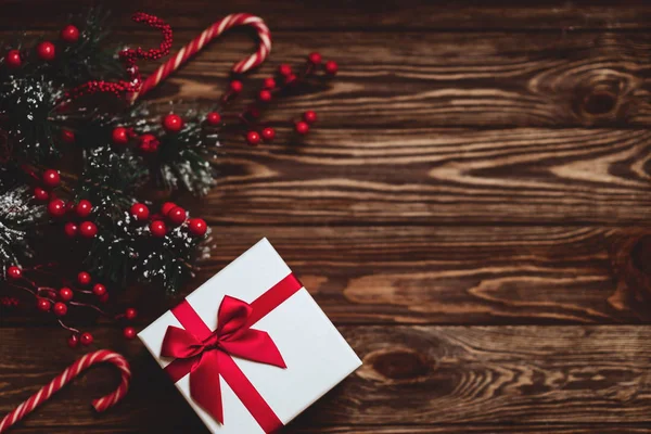 Presente de Natal com fita vermelha no fundo de madeira escura — Fotografia de Stock