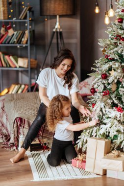 Anne ve çocuk yeni yıl ağacının arka planında bir yatakta.