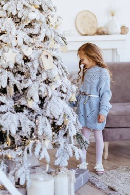 Noel hediyeleriyle küçük bir kız Noel ağacının yanında