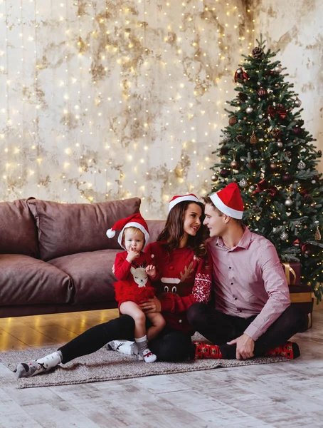 Young mother, father and her little daughter by a Christmas tree — Stockfoto