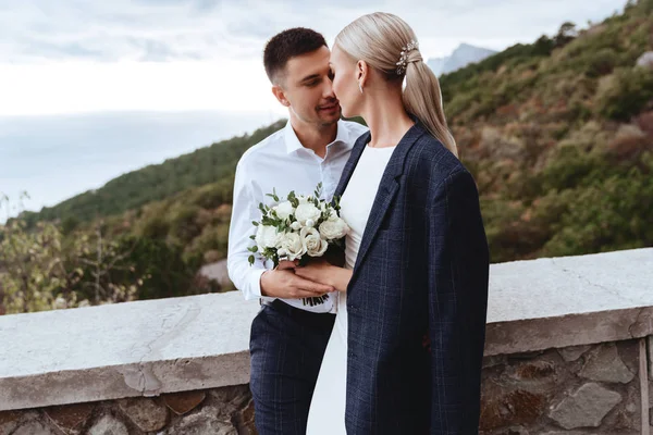 Joven pareja recién casada, novia y novio besándose, abrazándose a la vista perfecta de las montañas — Foto de Stock