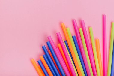 meyve suyu için renkli borular ve pembe arka planda kokteyller.
