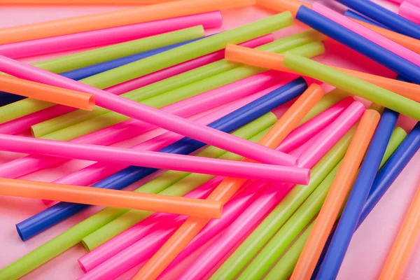 meyve suyu için renkli borular ve pembe arka planda kokteyller.