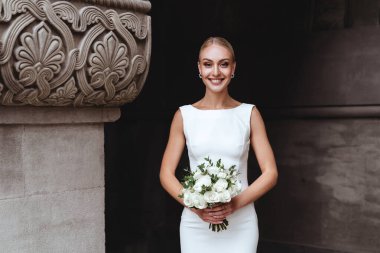 Güzel şık sarışın gelin eski kale duvarının yanında poz veriyor.