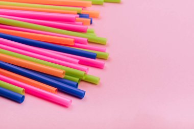 meyve suyu için renkli borular ve pembe arka planda kokteyller.