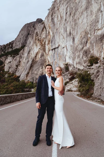 Joven pareja recién casada, novia y novio besándose, abrazándose a la vista perfecta de las montañas — Foto de Stock