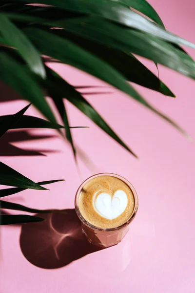 Morning coffee on the colorful background and palm branches. On blurred background with copy space.