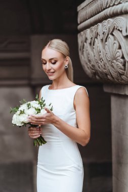 Güzel şık sarışın gelin eski kale duvarının yanında poz veriyor.