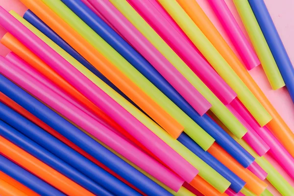 colored tubules for juice and cocktails on pink background.