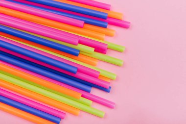 meyve suyu için renkli borular ve pembe arka planda kokteyller.