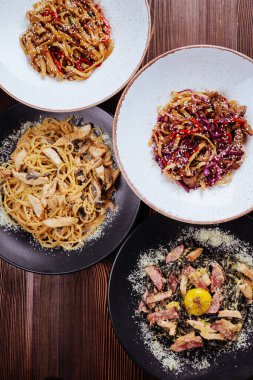 Ahşap arka planda farklı soslu birkaç tabak makarna..