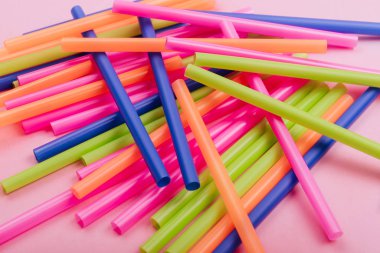 meyve suyu için renkli borular ve pembe arka planda kokteyller.