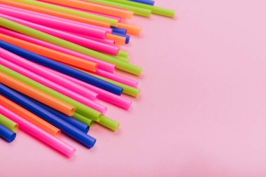 meyve suyu için renkli borular ve pembe arka planda kokteyller.