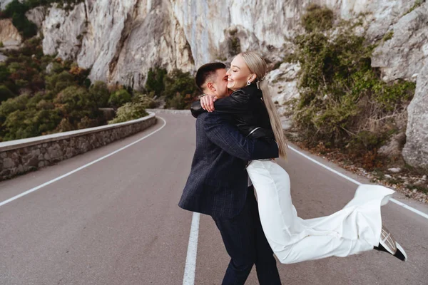 Joven pareja recién casada, novia y novio besándose, abrazándose a la vista perfecta de las montañas —  Fotos de Stock