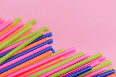 meyve suyu için renkli borular ve pembe arka planda kokteyller.