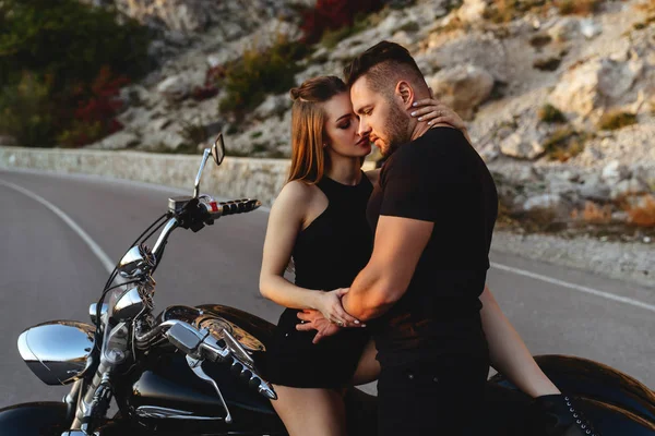 Bir çift aşık motosiklette öpüşüyor ve sarılıyor.