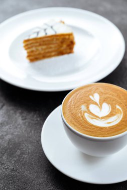 Siyah taşlı arka planda bir fincan kahve ve kek.