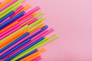 meyve suyu için renkli borular ve pembe arka planda kokteyller.