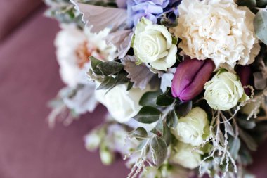 Zengin bir demet pembe şakayık ve leylak çiçekleri, cam vazoda yeşil yaprak.