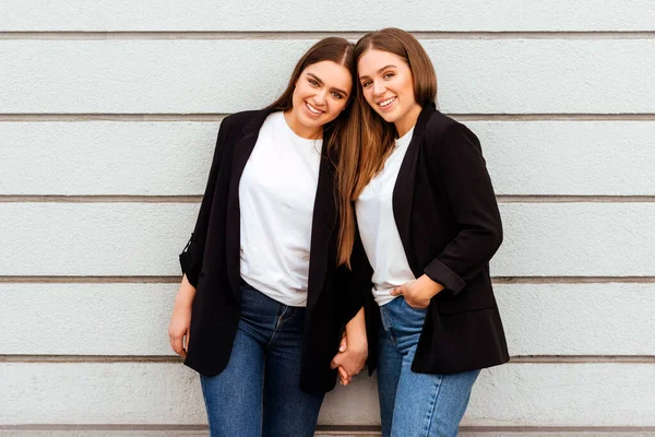 Dos chicas jóvenes atractivas de pie juntas y posando en la cámara . — Foto de Stock