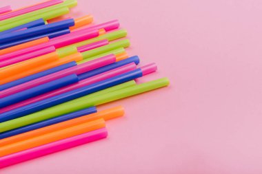 meyve suyu için renkli borular ve pembe arka planda kokteyller.
