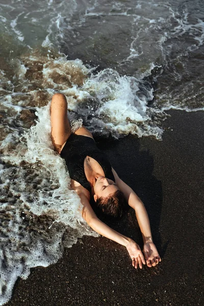 Retrato de una hermosa mujer de moda deportiva en bikini negro posando en verano cerca del océano —  Fotos de Stock