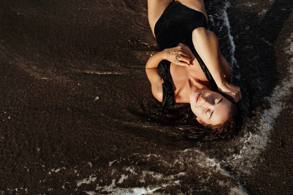 Retrato de una hermosa mujer de moda deportiva en bikini negro posando en verano cerca del océano —  Fotos de Stock