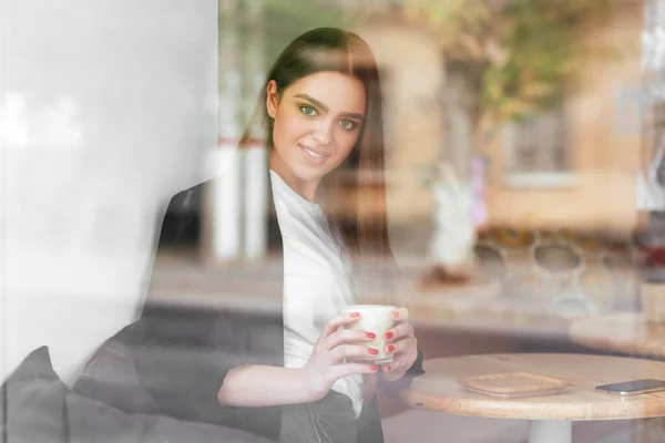 Young charming woman while sitting alone in coffee shop