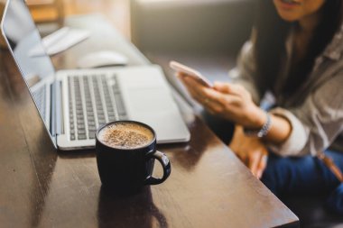 Genç bir kadın, Cafe 'de çalışırken dizüstü bilgisayar ve kahve bardağıyla çalışıyor..