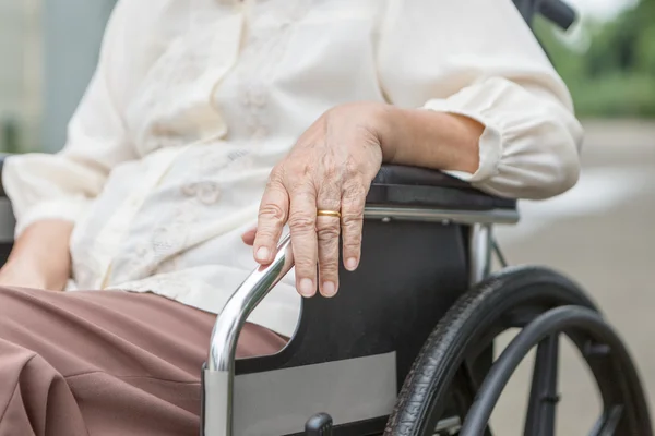 Mãos idosas em uma cadeira de rodas . — Fotografia de Stock